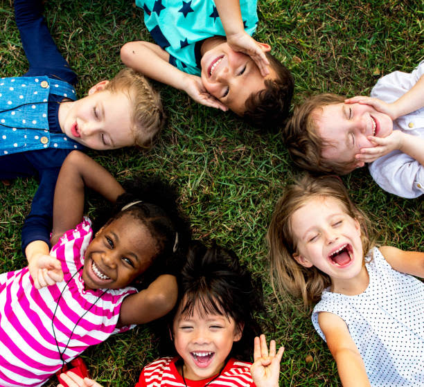 Diverse group of children laughing together on green grass