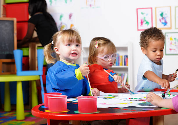 Toddlers exploring art and painting in a bright classroom