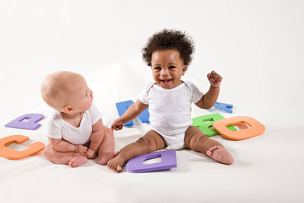 Two babies playing with colorful alphabet letters