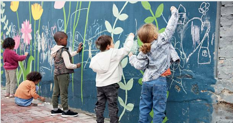 Children painting a vibrant outdoor wall mural together
